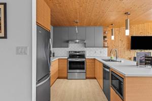 a kitchen with stainless steel appliances and wooden cabinets at Dolomites #203 - LEED Gold Certified in Canmore