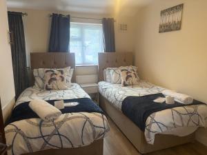 a bedroom with two beds and a window at D'Luxe Royal 3 bedrooms house in Abbeywood, London in Belvedere