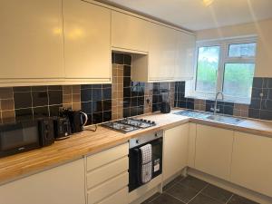 a kitchen with white cabinets and a stove top oven at D'Luxe Royal 3 bedrooms house in Abbeywood, London in Belvedere
