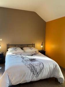 a bedroom with a large bed with white sheets at Le Daguet in Florenville
