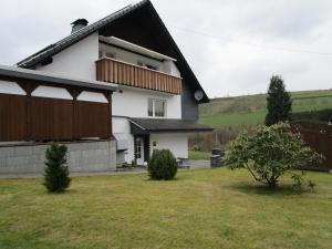 una casa blanca con techo negro y patio en Apartment Albers en Schmallenberg