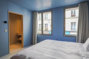 a blue bedroom with a bed and two windows at Suite d'exception Marais in Paris