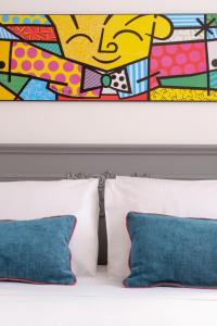 ein Gemälde über einem Bett mit zwei blauen Kissen in der Unterkunft Pietrenere39 in Pozzallo