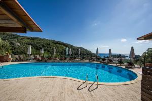 帕爾加的住宿－Enetiko Resort，一个带椅子和遮阳伞的游泳池