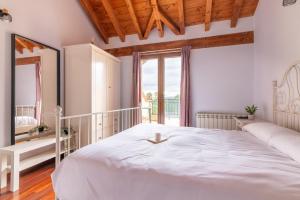 a bedroom with a large white bed and a window at Duplex cerca de la playa con piscina in Miengo