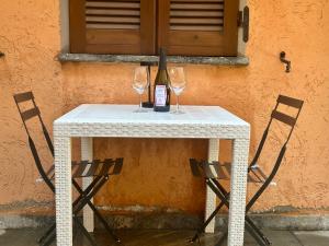 a white table with two glasses and a bottle of wine at Little Haven in Angera