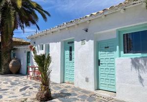 a white house with green doors and a palm tree at Casa Virgen de la Vega in Añover de Tajo