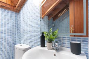 a blue tiled bathroom with a sink and a toilet at Duplex cerca de la playa con piscina in Miengo +9 photos