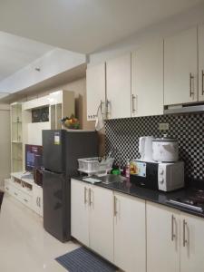 a kitchen with white cabinets and a black refrigerator at Sea Residences david in Manila +7 photos