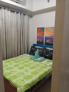 a bedroom with a bed with a green comforter at Sea Residences david in Manila