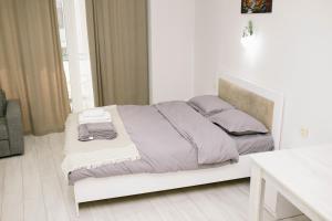 una camera bianca con letto con lenzuola e cuscini viola di Lumari Apartment a Kakhaberi