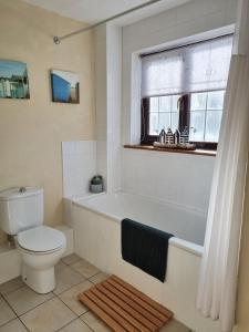 ein Badezimmer mit Badewanne und Toilette und einem Fenster in der Unterkunft Bay Tree Cottage - cosy home near beach in Woolacombe