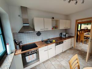 a kitchen with white cabinets and a sink at Forest Escape with Terrace in Eisfeld
