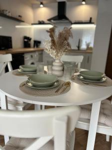 una mesa de comedor blanca con platos verdes. en Apartament Kosynierów, en Przemyśl