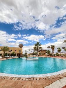 a large swimming pool with palm trees and a cloudy sky at Les Jardins d Amizmiz 6 piscines in Amizmiz
