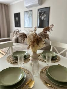 una mesa con platos verdes y un jarrón con flores en Apartament Kosynierów, en Przemyśl