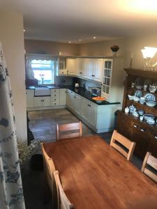 a kitchen with a wooden table and a dining room at Carraig Ban Cottage Dungloe in Ardeevin