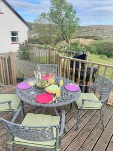 a table and chairs on the deck of a house at Carraig Ban Cottage Dungloe in Loughanure +55 photos