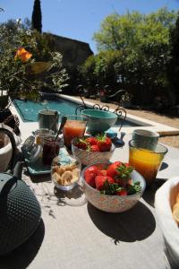 una mesa con tazones de comida y fruta. en Le Jardin de Mazan en Mazan