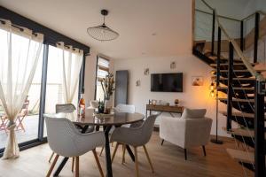 a dining room with a table and chairs and a staircase at L'avocette Gîtes de la réserve in Grand-Laviers
