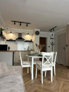 Una cocina y un comedor con una mesa y sillas blancas. en Apartament Kosynierów, en Przemyśl