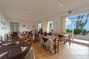 a restaurant with tables and chairs and a large window at Hotel Voce del Mare in Capoliveri