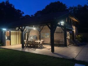a pavilion with a table and chairs on a patio at night at Gavial - Grande maison avec piscine in Léon