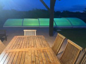 a wooden table and chairs with a bench in the background at Gavial - Grande maison avec piscine in Léon