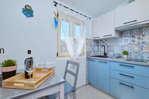 eine Küche mit blauen Schränken und einem Tisch mit einem Glas Wein in der Unterkunft Cozy Holiday Home Punta Kriza in Punta Križa + 20 Fotos
