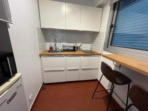 a small kitchen with white cabinets and a counter at Studio cosy in Arcachon