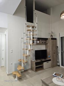 a living room with a spiral staircase and a television at Angelo Apartments in Paralía Avdhíron