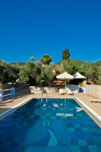 una piscina con sombrilla y una casa en Aretousa Studios & Apartments, en Skopelos Town