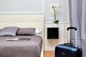 ein Schlafzimmer mit einem Bett mit einem Koffer und einem TV in der Unterkunft St. Peter Vatican Rooms in Rom
