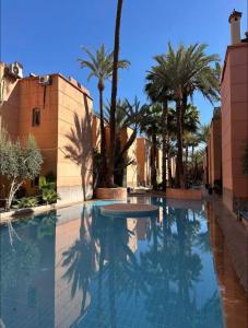 einen Pool mit Palmen und blauem Himmel in der Unterkunft Riad De Luxe Marrakech in Marrakesch