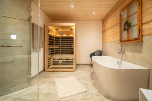 ein Badezimmer mit Badewanne und Glasdusche in der Unterkunft Luxus Chalet im Allgäu - Zirbenholz Schlafzimmer - Terrasse mit Bergblick - Infrarotkabine in Blaichach + 37 Fotos