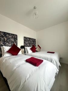two white beds with red pillows in a room at Welsh Getaway Apartment 2 - Town Centre in Dowlais