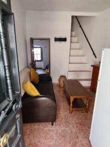 a living room with a black leather couch and stairs at Casa Rincón de Monda in Monda