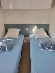 two beds sitting next to each other in a room at Mobilhome neuf 3 chambres Oléron in Saint-Denis-dʼOléron +15 photos