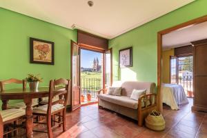 a living room with green walls and a table and chairs at Apartamentos El Cruce de Moratón in Cóbreces