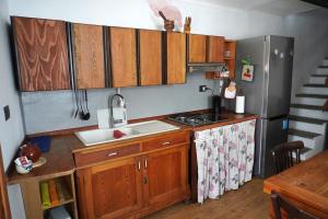 a kitchen with wooden cabinets and a sink and a refrigerator at Casa nella valle in Groscavallo