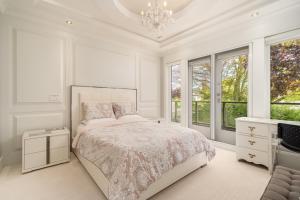 a white bedroom with a bed and a chandelier at Vancouver Shangrila House in Richmond