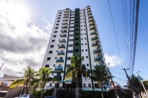 a tall white building with palm trees in front of it at Frente mar, wi-fi, estacionamento, smart TV in Praia Grande