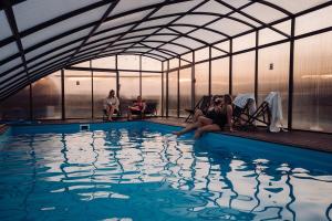 a group of people sitting around a swimming pool at Domki na Kaszubach - Chabry i Rumianki - Roztoka, Przywidz - Basen Sauna Jacuzzi KASZUBY in Roztoka