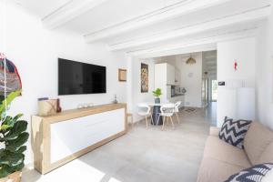 Una sala de estar con un televisor de pantalla plana en una pared blanca. en La Selva - Marlù House -, en Cabras