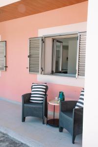 eine Terrasse mit 2 Stühlen und einem Tisch vor einer rosa Wand in der Unterkunft Just Like Home - Casa Rosa in Padornelo