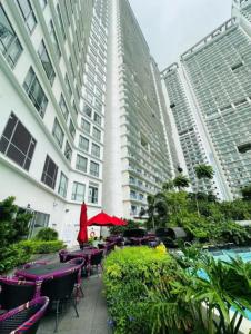 a patio with tables and chairs in front of a building at Novotel Acqua Residences by Jolly Luxe Suites in Manila +75 photos