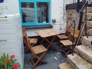 twee stoelen en een tafel op een veranda met een raam bij Penzer Cottage in Mousehole