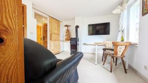 a living room with a black leather couch and a table at Randfichte - die Hütte direkt am Wald in Neudörfel
