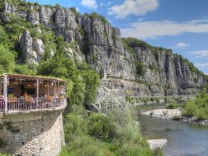a restaurant on the side of a mountain next to a river at Studio cosy avec piscine privative in Saint-Sernin