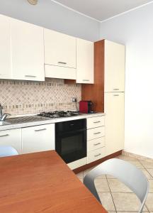 Una cocina con gabinetes blancos y una mesa y una silla. en Appartamento Casa Bruno, en Porto SantʼElpidio